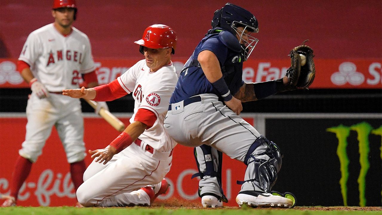 Los Angeles Angels' Jason Castro, center, scores on a double by Brian Goodwin as Seattle Mariners catcher Joseph Odom, right, takes a late throw during the sixth inning of a baseball game Wednesday, July 29, 2020, in Anaheim, Calif. (AP Photo/Mark J. Terrill)