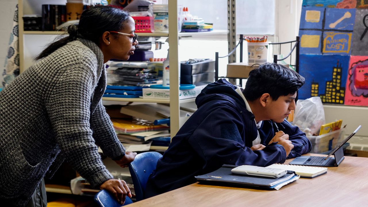 S'Heelia Marks gives instruction to Elijah Nicolas Hernandez-Valeriano as he prepares for the digital SAT, Wednesday, March 6, 2024, at Holy Family Cristo Rey Catholic High School in Birmingham, Ala.