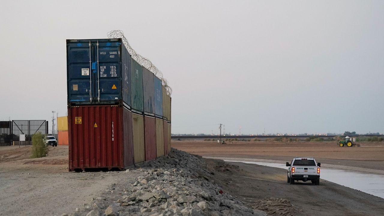 Border Patrol agents patrol along a line of shipping containers stacked near the border Tuesday, Aug. 23, 2022, near Yuma, Ariz. (AP Photo/Gregory Bull)