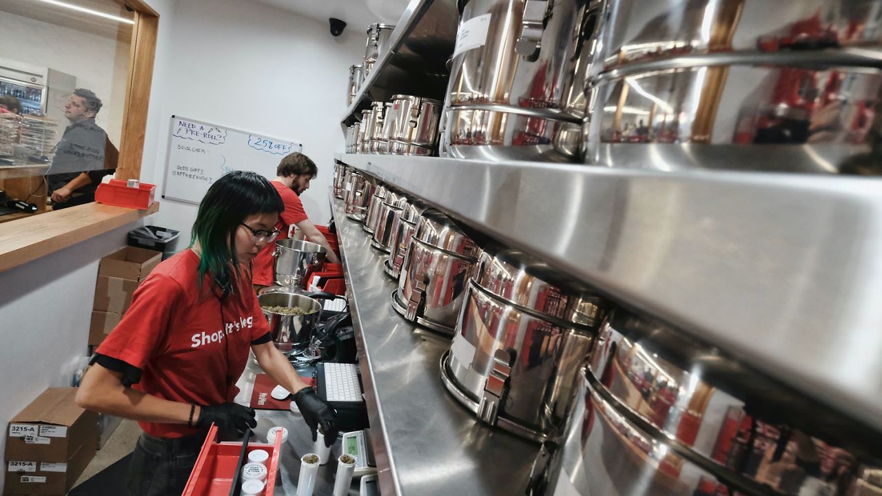 In this Jan. 12, 2018, file photo, a bud tender prepares marijuana for a customer at Med Men a dispensary in West Hollywood, Calif. Leading California cannabis companies Friday, Dec. 17, 2021, warned Gov. Gavin Newsom that the state's legal industry was on the verge of collapse and needed immediate tax cuts and a rapid expansion of retail outlets to steady the marketplace. (AP Photo/Richard Vogel,Ffile)