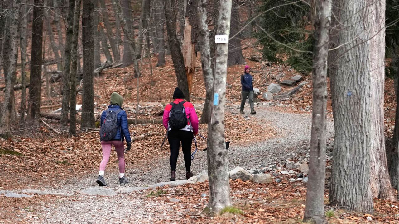 Hikers head up a trailhead of Great Blue Hill, while one completes her hike from the summit, at the Blue Hills Reservation, Wednesday, Dec. 28, 2022, in Milton, Mass. (The Associated Press)