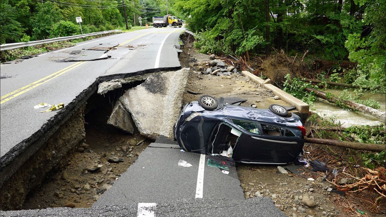 A damaged car lays on a collapsed roadway along Route 32 in the Hudson Valley near Cornwall, N.Y., Monday, July 10, 2023. Heavy rain has washed out roads and forced evacuations in the Northeast as more downpours were forecast throughout the day. (AP Photo/Paul Kazdan)