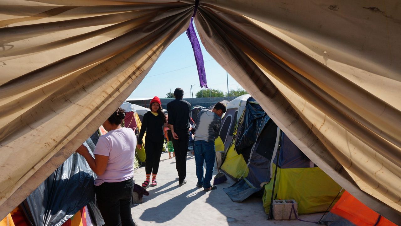 Migrants walk by their tents in the Senda de Vida 2 shelter in Reynosa, Mexico, Thursday, Dec. 15, 2022. (AP Photo/Giovanna Dell'Orto)