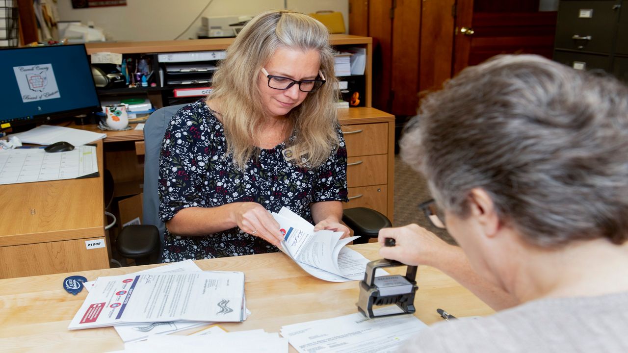 Carroll County Board of Elections Clerk Sarah Dyck, foreground, stamps incoming absentee ballot applications as Elections Clerk Deloris Kean counts more applications at the Board of Elections offices in Carrollton, Ohio, Sept. 26, 2022. (AP Photo/Phil Long)