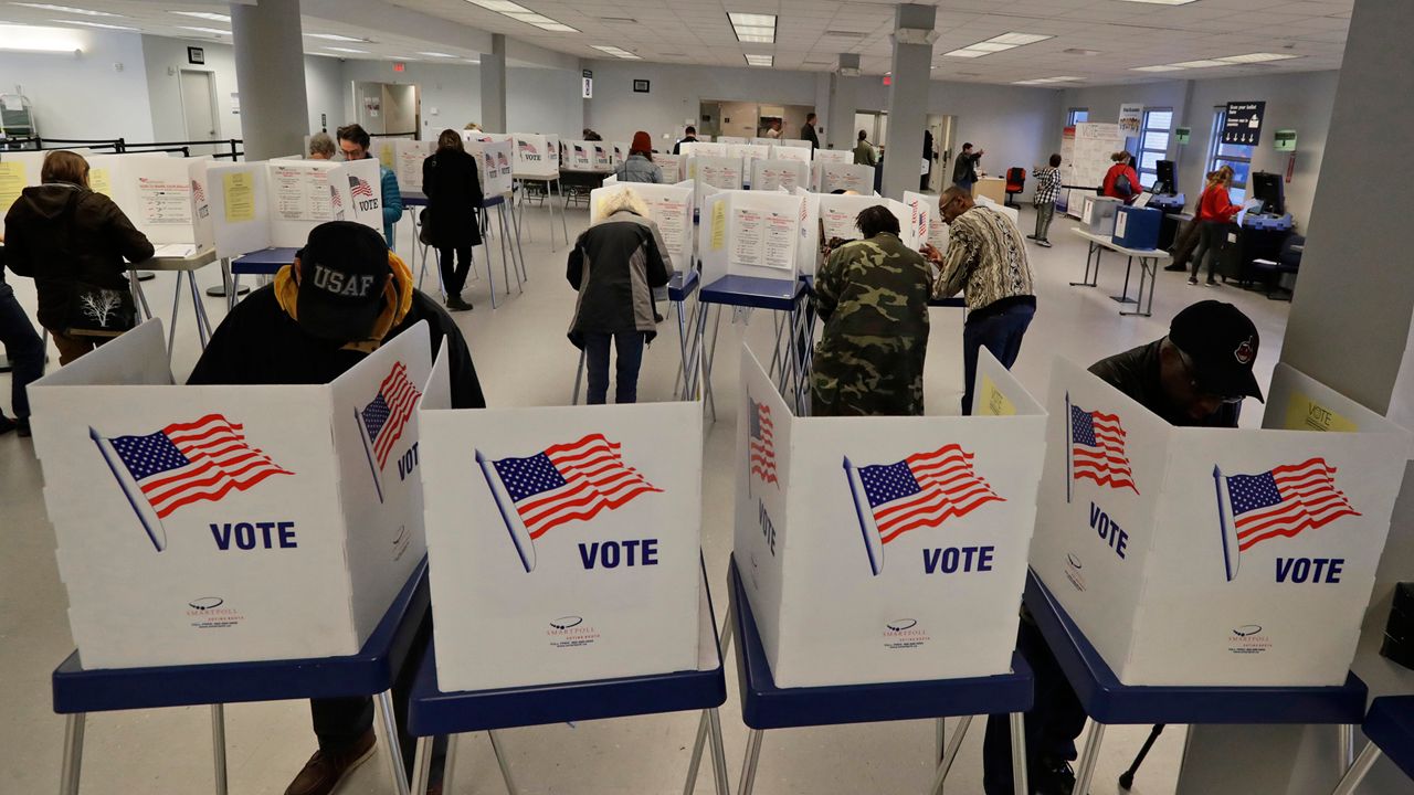 Voters complete ballots behind cardboard shields labled 'vote' in an Ohio polling place. 