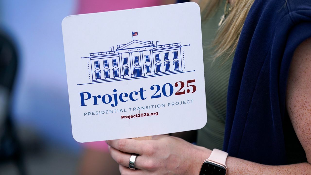 Kristen Eichamer holds a Project 2025 fan in the group's tent at the Iowa State Fair, Aug. 14, 2023, in Des Moines, Iowa. (AP Photo/Charlie Neibergall)