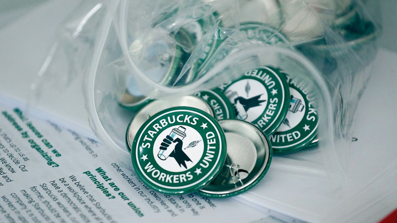 Pro-union pins sit on a table during a watch party for Starbucks' employees union election, Dec. 9, 2021, in Buffalo, N.Y. On Monday, Jan. 10, 2022, the National Labor Relations Board confirmed that a second Starbucks store near Buffalo has voted to unionize, one of a growing number of the coffee chain’s stores seeking to organize workers. (AP Photo/Joshua Bessex, File)