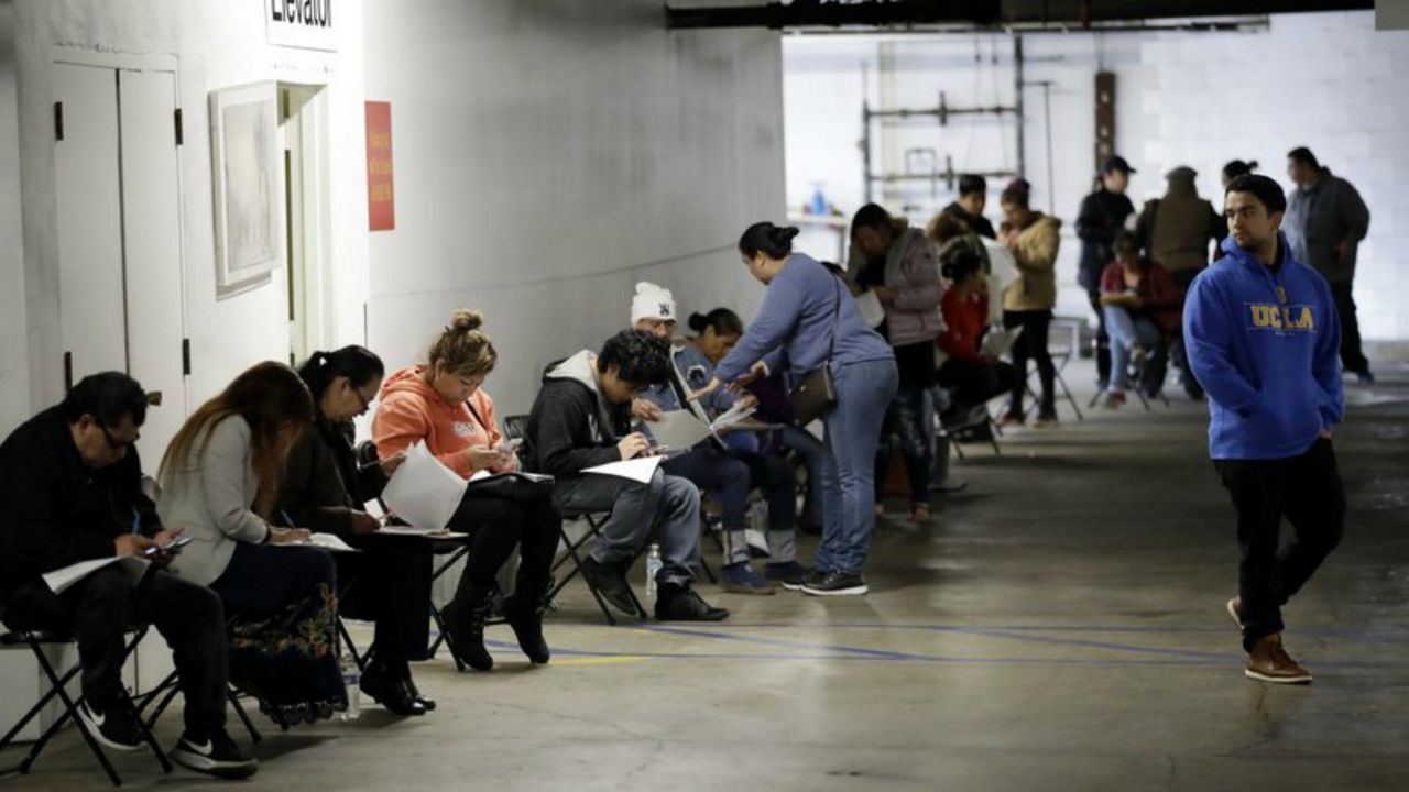 FILE - In this March 13, 2020 file photo, unionized hospitality workers wait in line in a basement garage to apply for unemployment benefits at the Hospitality Training Academy in Los Angeles. More than 6.6 million Americans applied for unemployment benefits last week, far exceeding a record high set just last week, a sign that layoffs are accelerating in the midst of the coronavirus. (AP Photo/Marcio Jose Sanchez, File)