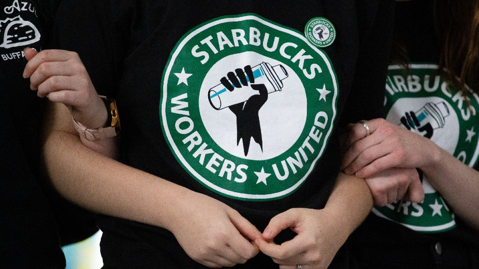 Starbucks Workers United interlock arms in stance to unionize. (AP)