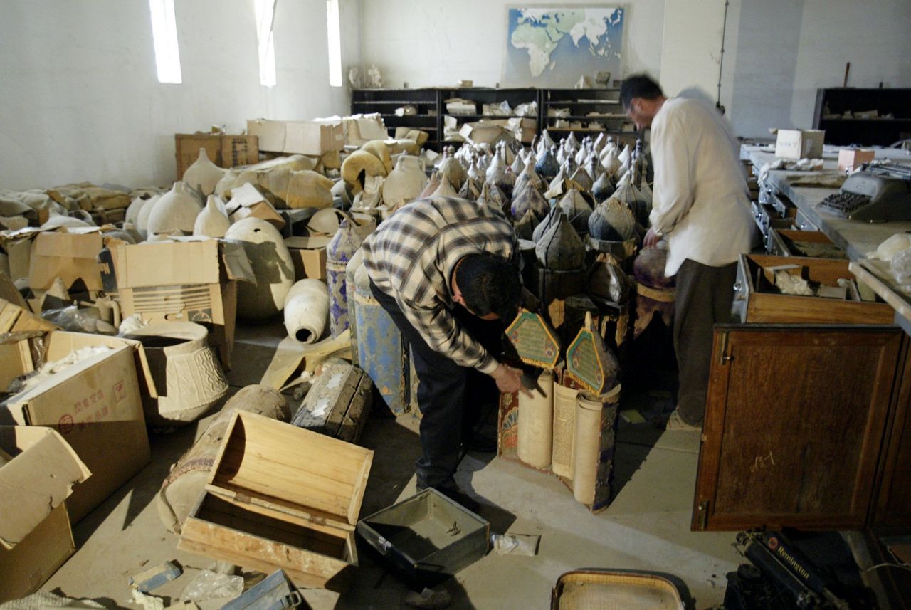 Civilians inspect Torah scrolls stored in the vault of the National Museum in Baghdad, Iraq Saturday April 12, 2003 after looting the of the museum began. (AP Photo/Jerome Delay)