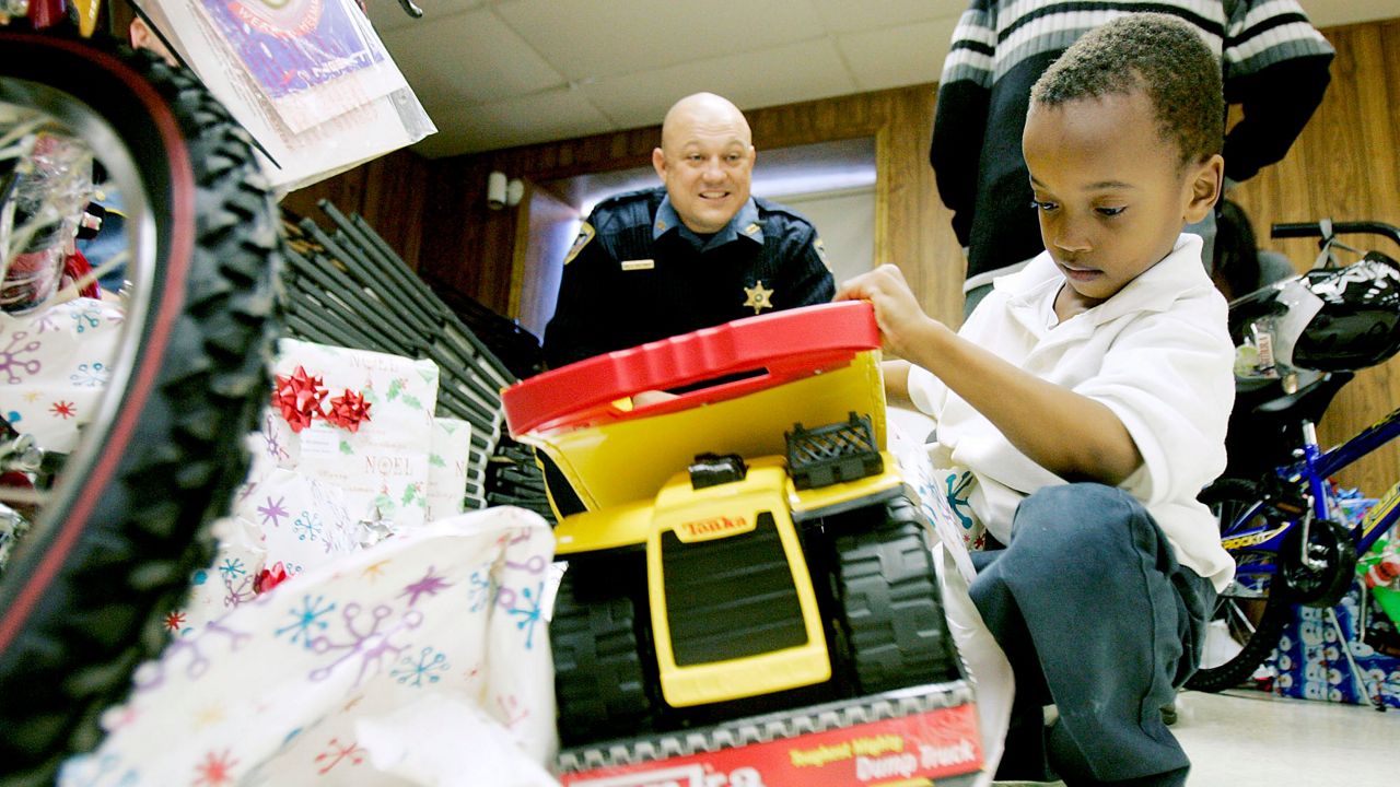 Jahovah Robinson, 6, rips the wrapping off a Tonka truck while Terrebonne Parish Sheriff Detective Jody Foret watches Monday Dec. 17, 2007 at the Terrebonne Parish Sheriff Rifle Range in Houma La. (AP Photo/The Houma Courier, Matt Stamey)