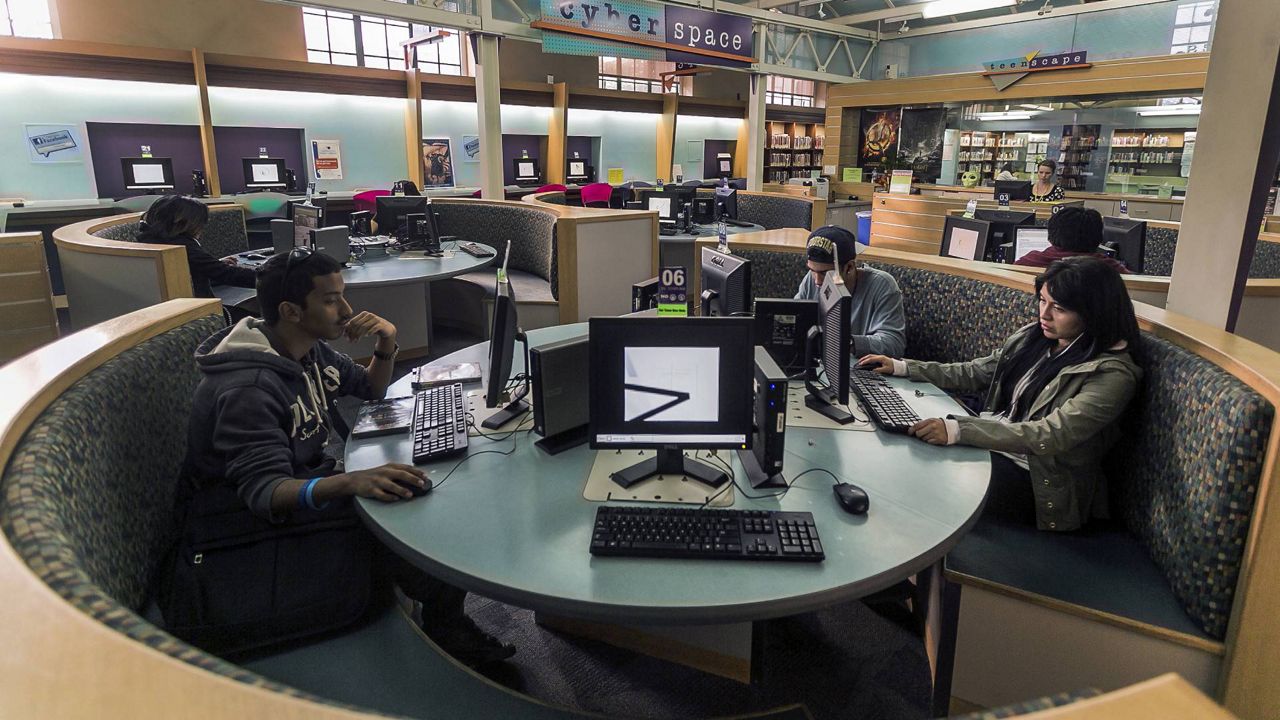 In this Jan. 8, 2014 photo, patrons use computers in the Teen'Scape area at the Los Angeles Public Library in LA. (AP Photo/Damian Dovarganes)