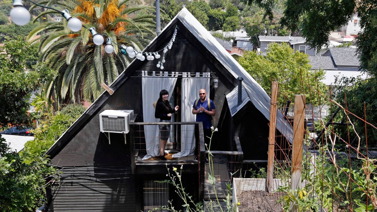 In this May 19, 2014, file photo, Airbnb guests Camille Smithwick and James Green from Manchester, England, pose for photos at an Airbnb property owned by ceramist Jonathan Entler in the Echo Park area of Los Angeles. (AP Photo/Damian Dovarganes)