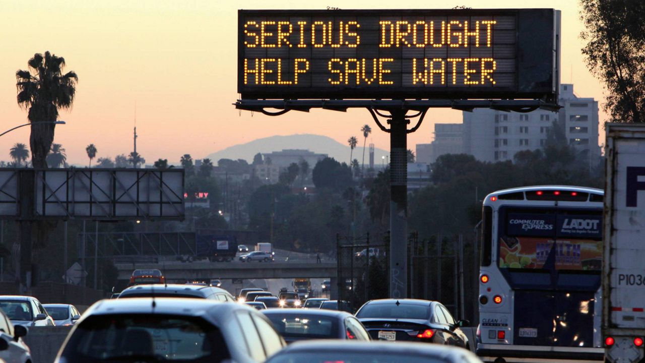 In this Friday, Feb. 14, 2014, file photo, morning traffic makes its way toward downtown Los Angeles along the Hollywood Freeway past an electronic sign warning of severe drought. (AP Photo/Richard Vogel)