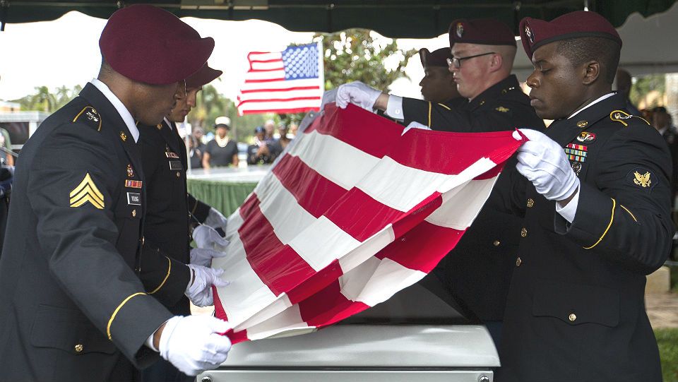 Sgt. Donald Young places a U.S. flag over the casket of Sgt. La David Johnson during his burial service at Fred Hunter's Hollywood Memorial Gardens in Hollywood, Fla., on Saturday, Oct. 21, 2017. Mourners remembered not only a U.S. soldier whose combat death in Africa led to a political fight between President Donald Trump and a Florida congresswoman but his three comrades who died with him. (Matias J. Ocner/Miami Herald via AP)