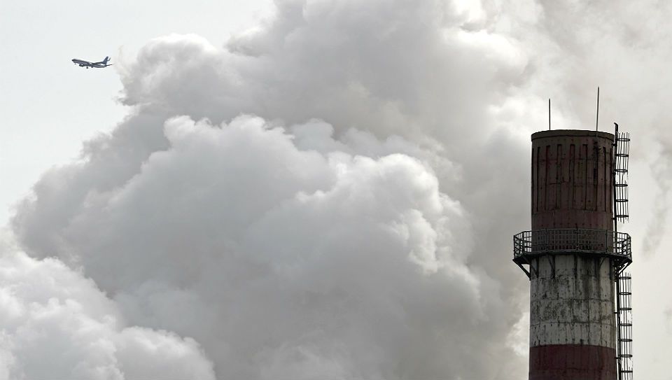 FILE - In this Feb. 28, 2017 file photo, a passenger airplane flies behind steam and white smoke emitted from a coal-fired power plant in Beijing. On Monday, Nov. 13, 2017, scientists projected that global carbon pollution has risen in 2017 after three straight years when the heat-trapping gas didn’t go up at all. (AP Photo/Andy Wong, File)