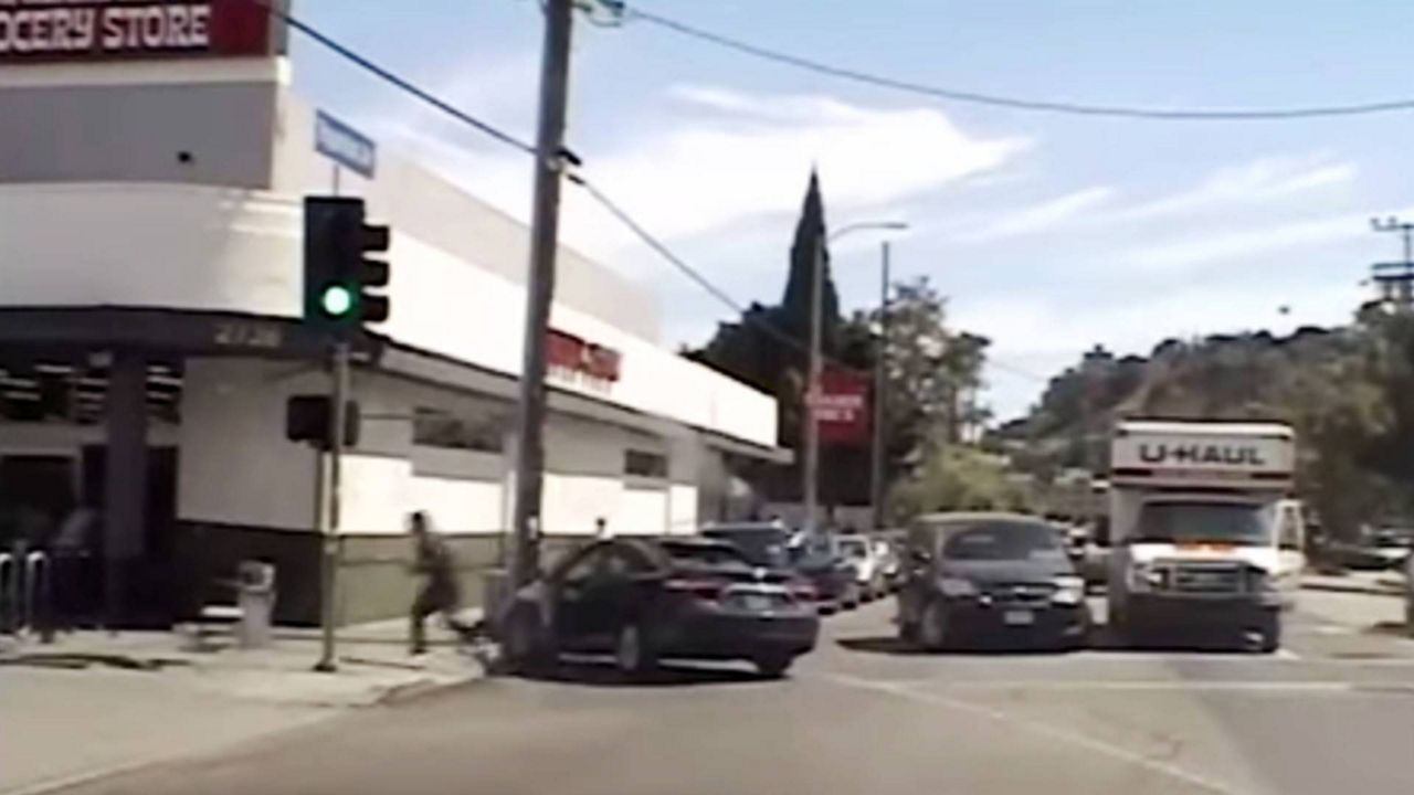 In this July 21, 2018 frame from patrol car video released by the LAPD, suspect Gene Evin Atkins runs into a Trader Joe's market after crashing his car at the end of a chase and firing rounds at officers pursuing him in LA. (LAPD via AP)