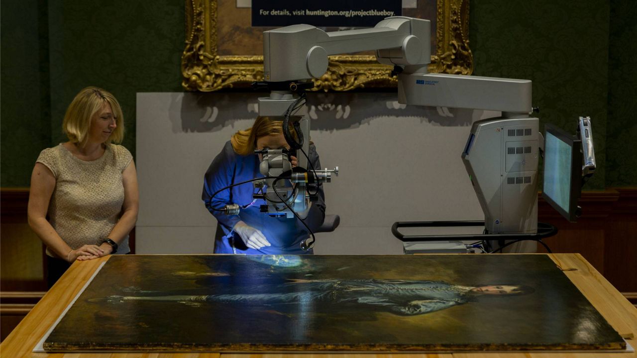 In this Sept. 20, 2018, photo, The Huntington's senior paintings conservator, Christina O'Connell, right, examines "The Blue Boy" painting at The Huntington in San Marino, Calif. (AP Photo/Damian Dovarganes)