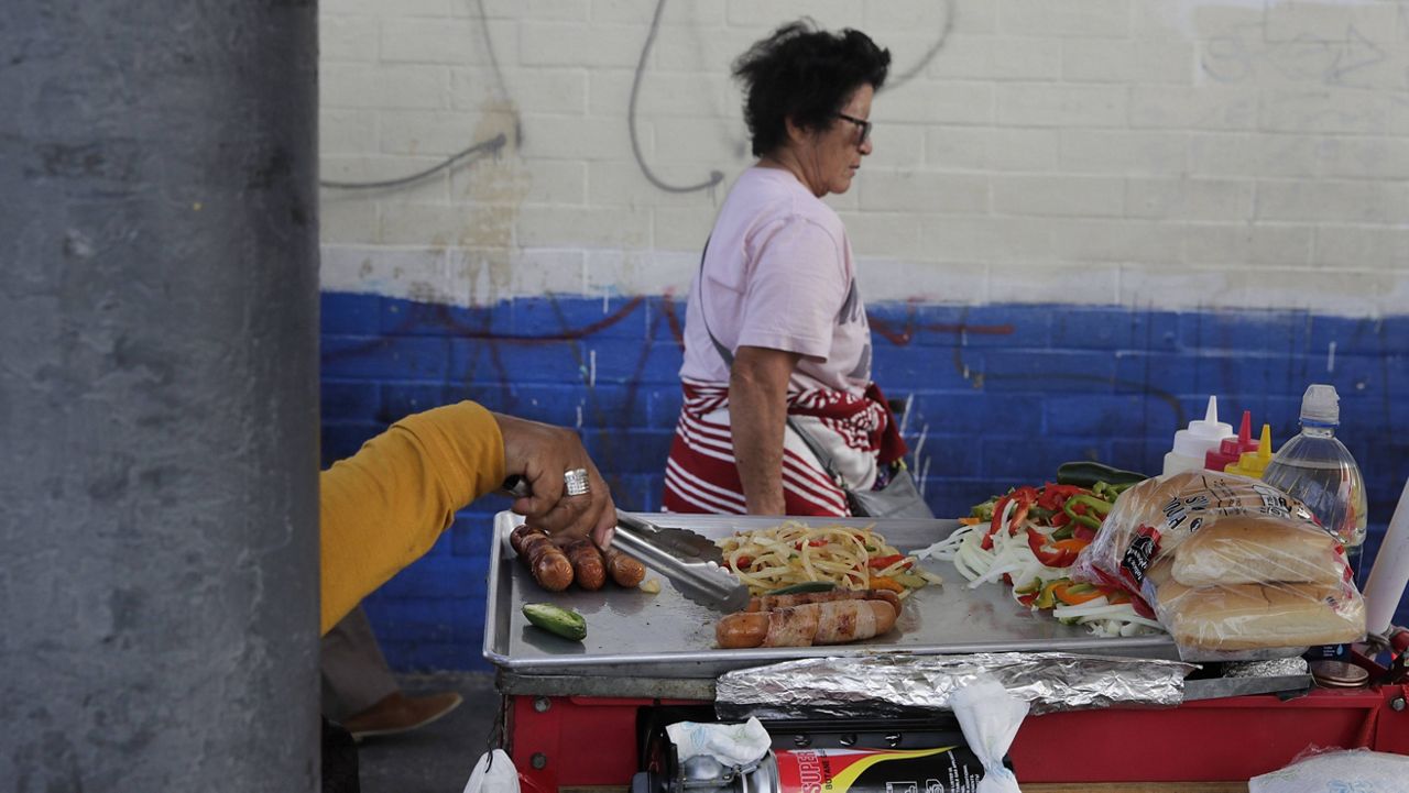 A food vendor prepares hot dogs on a sidewalk Tuesday, Nov. 27, 2018, in Los Angeles. (AP Photo/Jae C. Hong)