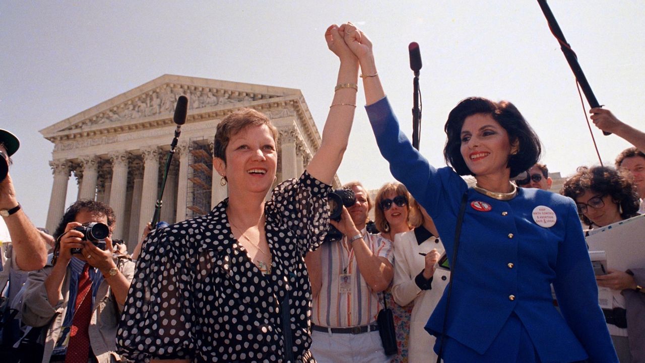 FILE - In this Wednesday, April 26, 1989 file photo, Norma McCorvey, Jane Roe in the 1973 court case, left, and her attorney Gloria Allred hold hands as they leave the Supreme Court building in Washington after sitting in while the court listened to arguments in a Missouri abortion case. (AP Photo/J. Scott Applewhite, File)