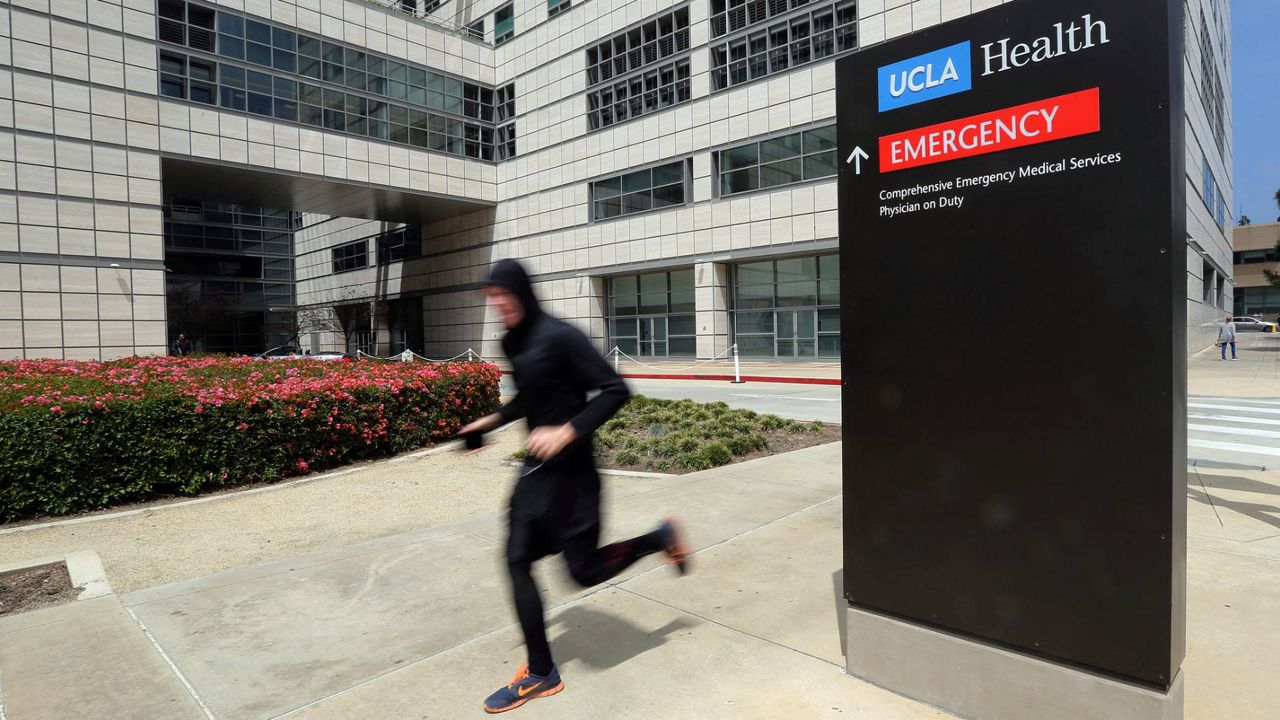 In this April 26, 2019, file photo, a runner passes the Ronald Reagan UCLA Medical Center on the campus of the University of California, Los Angeles. (AP Photo/Reed Saxon)