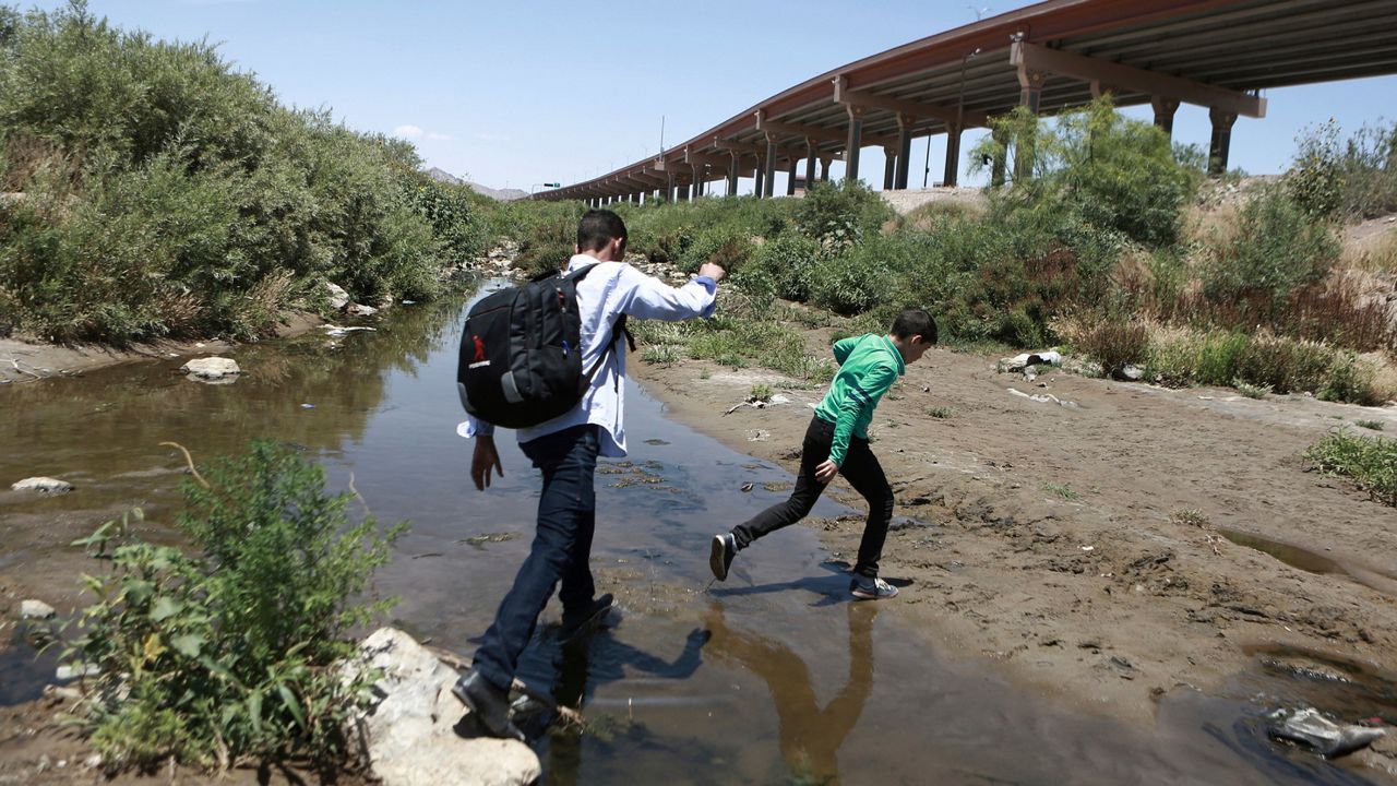 FILE - In this June 7, 2019 file photo, people cross the Rio Grande into the United States to turn themselves over to authorities and ask for asylum, as seen from Ciudad Juarez, Chihuahua, Mexico, opposite El Paso, Texas. (AP Photo/Christian Torres, File)