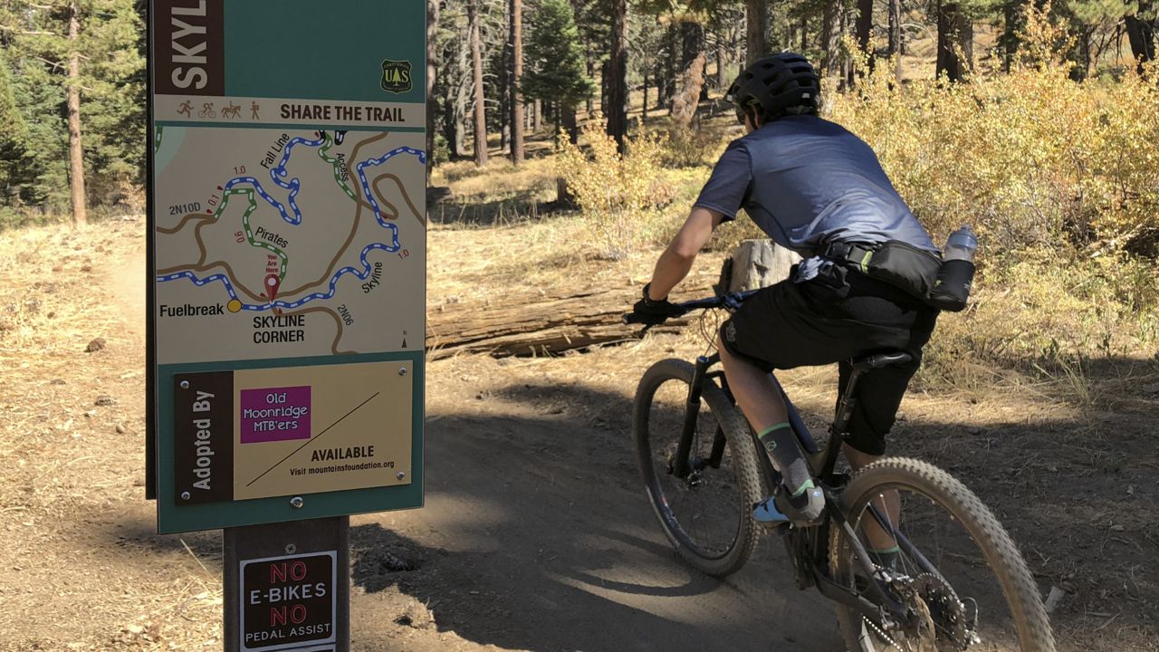 In this photo taken Sept. 23, 2018, a mountain biker pedals past a No E-bikes sign in the San Bernardino National Forest near Big Bear Lake, Calif. (Brian Melley/AP)