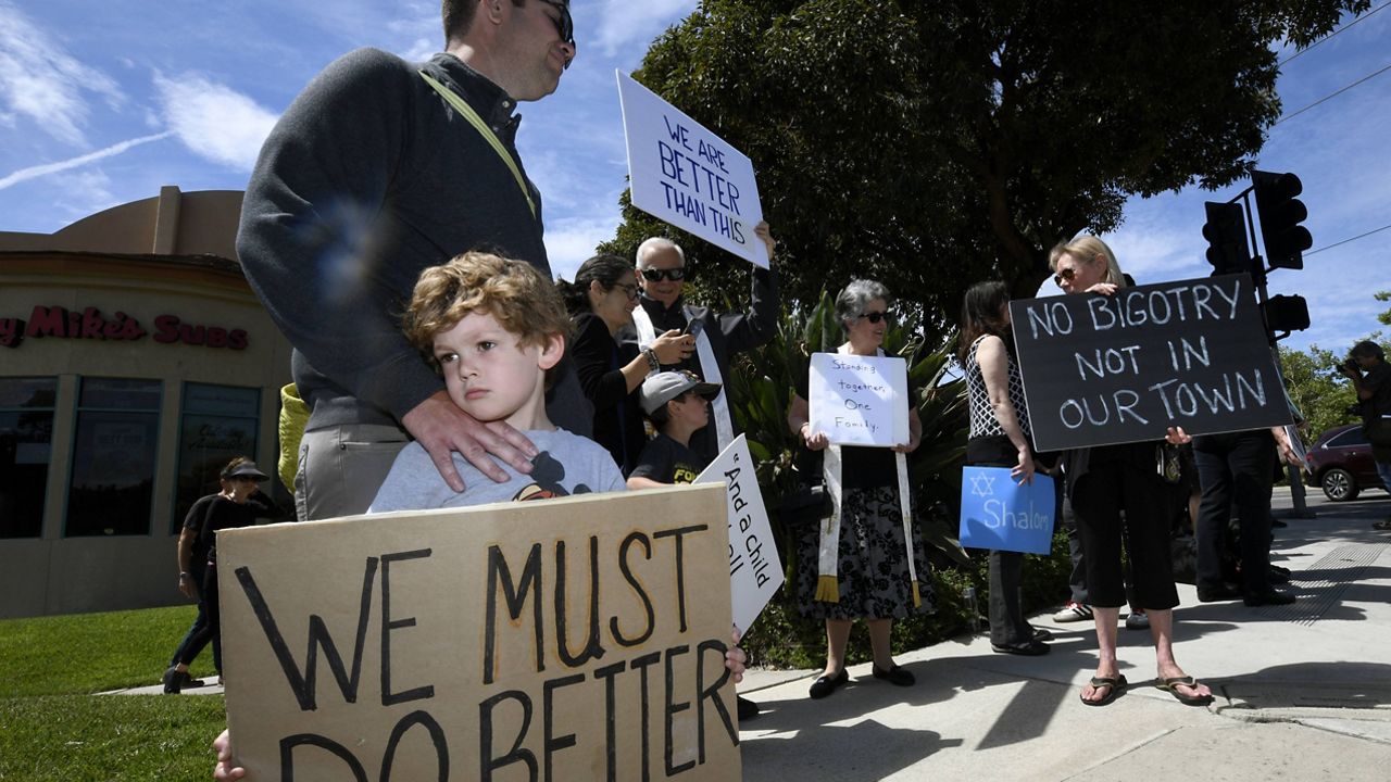 In this April 28, 2019 photo Kyle Fox is shown holding a sign with his father, Brady Fox, in support of the victims of Chabad of Poway synagogue shooting in Poway, Calif. (AP Photo/Denis Poroy, File)