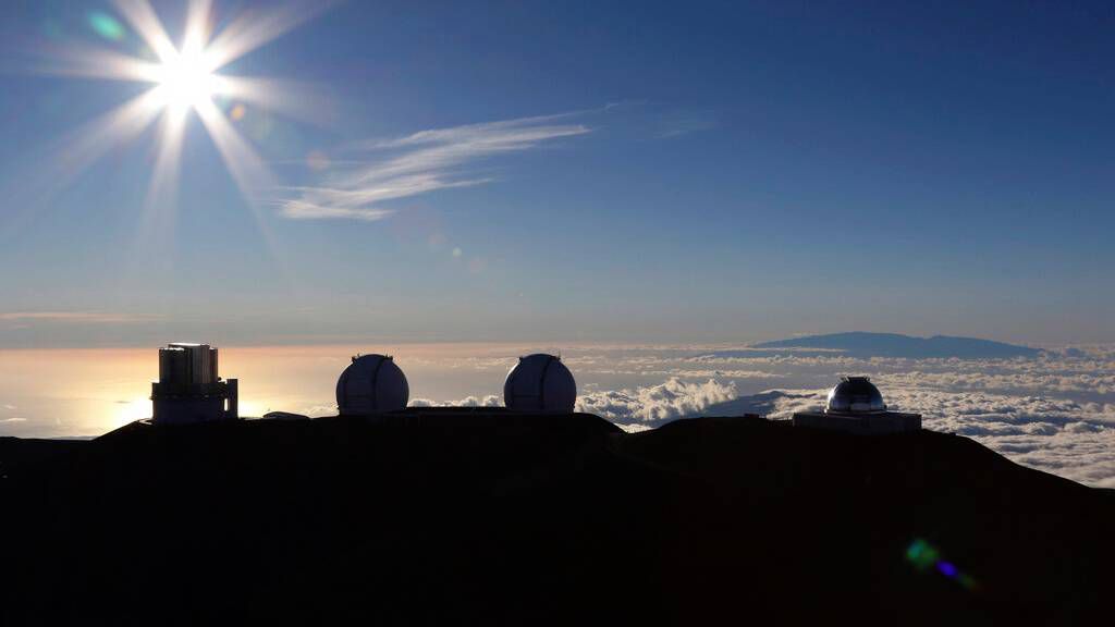 In this Sunday, July 14, 2019, file photo, the sun sets behind telescopes at the summit of Mauna Kea in Hawaii. (AP Photo/Caleb Jones, File)