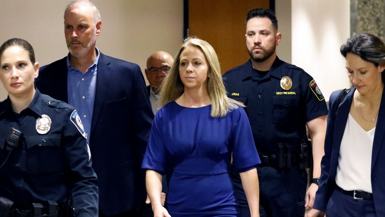 In this Tuesday, Sept. 24, 2019, Amber Guyger, center, walks flanked by security while arriving for her murder trial at the Frank Crowley Courthouse in downtown Dallas. Security has been ramped up around the white former Dallas police officer’s high-profile trial for murder in the killing of her unarmed black neighbor. The Dallas Police Association says threats have forced the group to hire private security for Guyger and her lawyers. (AP Photo/LM Otero)