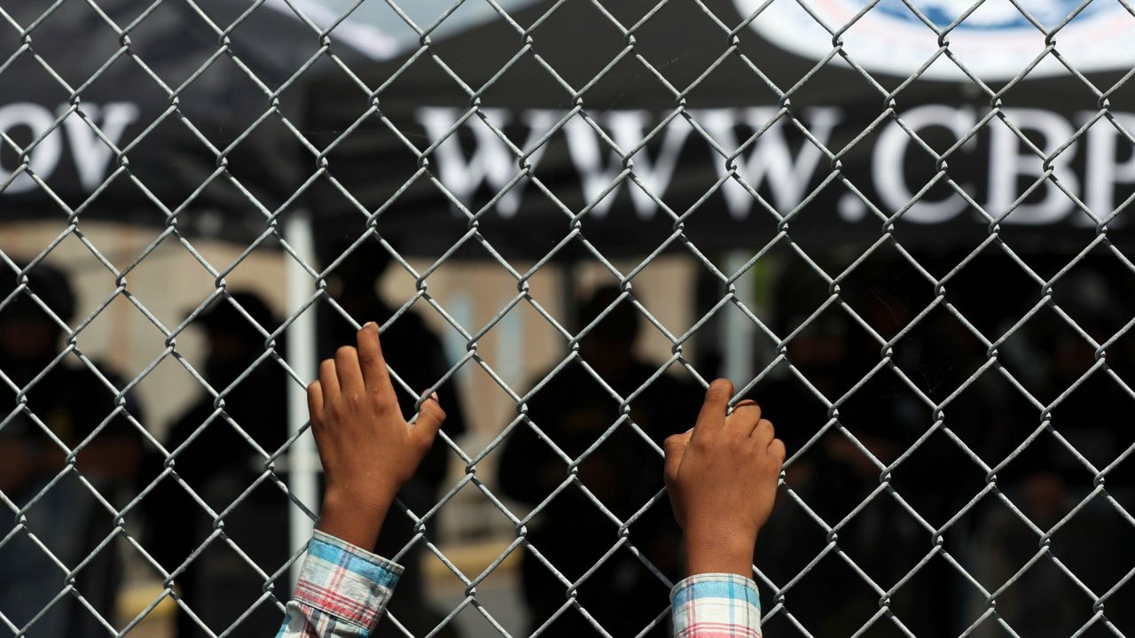 A migrant leans on a fence of the Gateway International Bridge that connects downtown Matamoros, Mexico with Brownsville, Texas, Thursday, Oct. 10, 2019. (AP Photo/Fernando Llano)