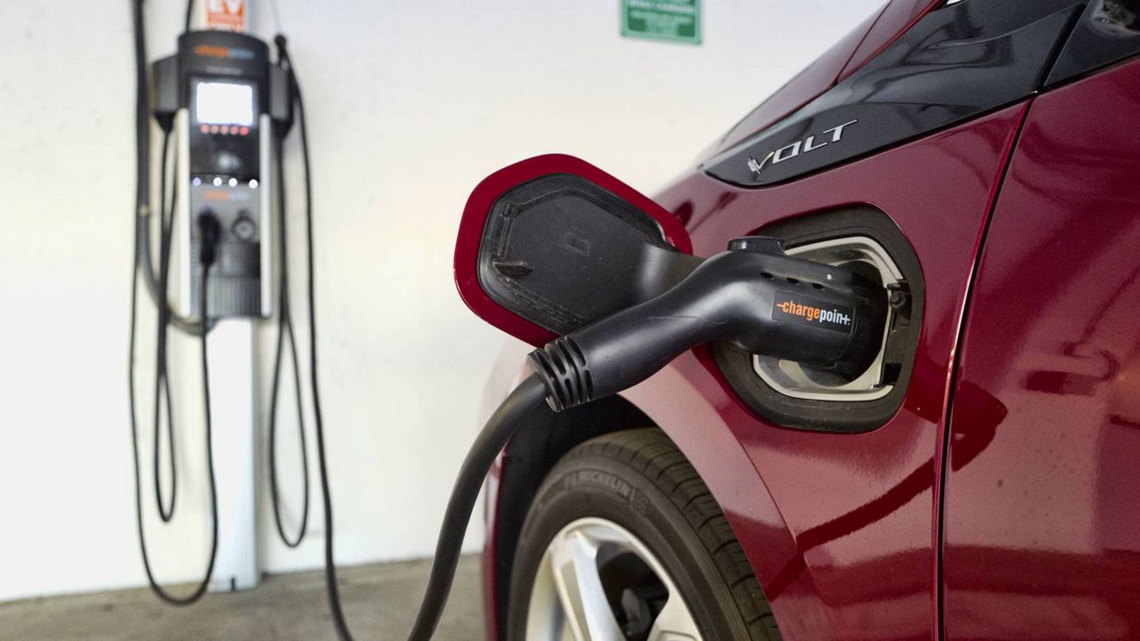 This Oct. 17, 2018, file photo shows a Chevrolet Volt hybrid car charging at a ChargePoint charging station at a parking garage in Los Angeles. (AP Photo/Richard Vogel, File)