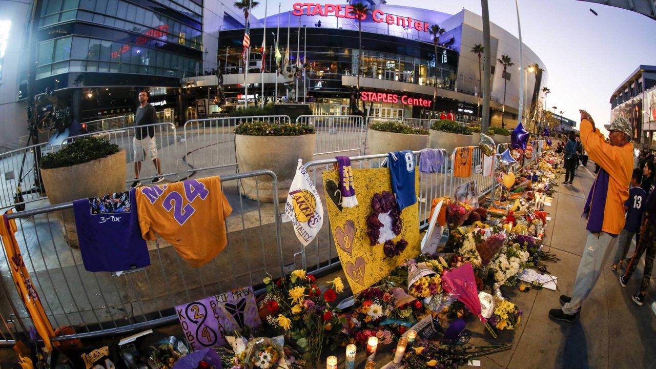 Flowers, basketballs, sweat shirts, candles, and message notes are placed at a memorial for Kobe Bryant in front of Staples Center Tuesday, Jan. 28, 2020, in Los Angeles. (AP Photo/Ringo H.W. Chiu)