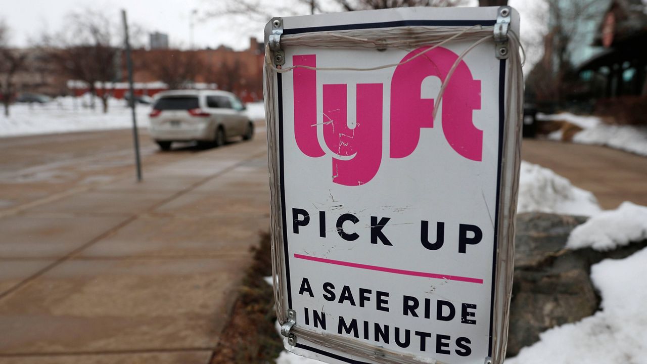 In this Feb. 12, 2020, file photo, a sign marks the pickup lane for Lyft rides outside the Pepsi Center in Denver. (AP Photo/David Zalubowski, File)