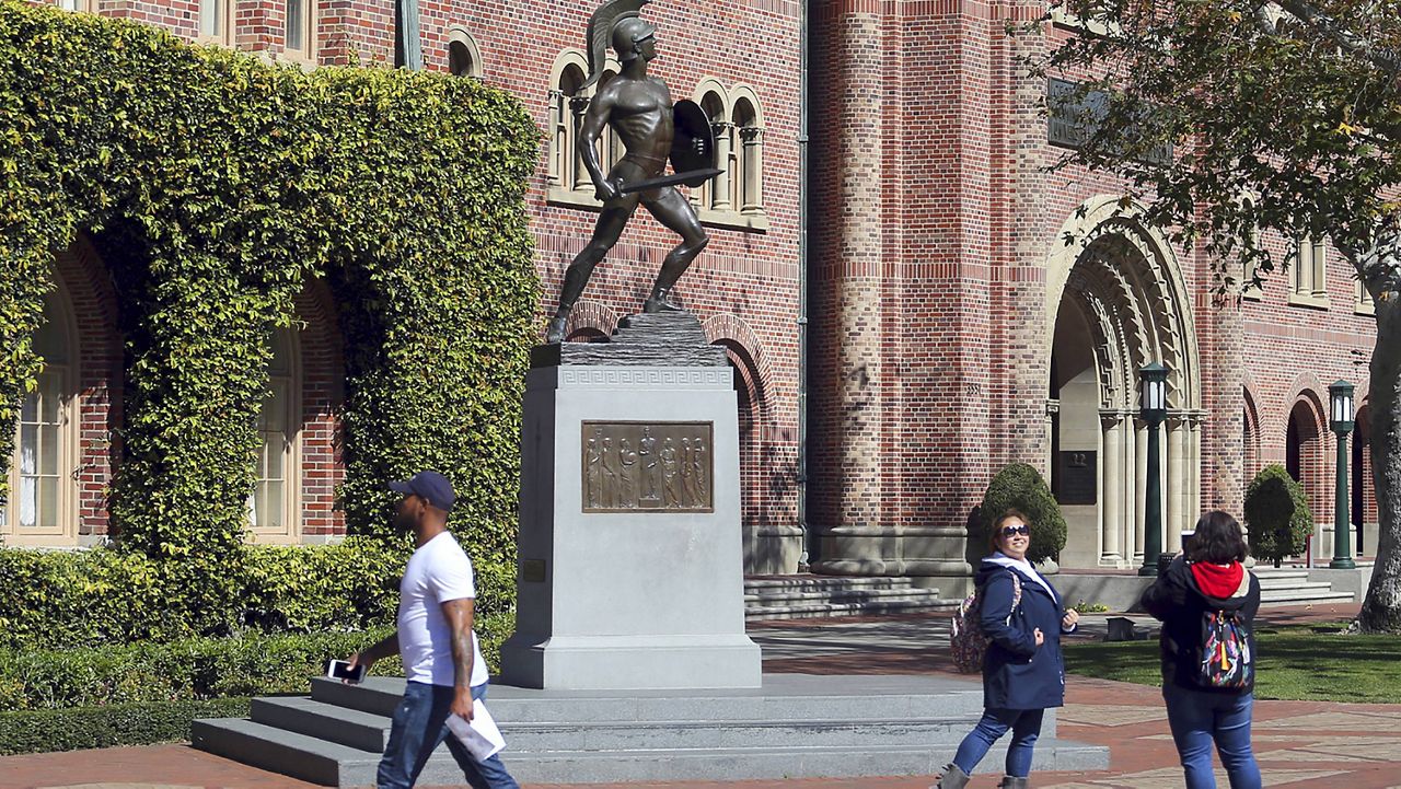 People pose for photos in front of the iconic Tommy Trojan statue on the campus of the University of Southern California in Los Angeles on March 12, 2019. (AP Photo/Reed Saxon)