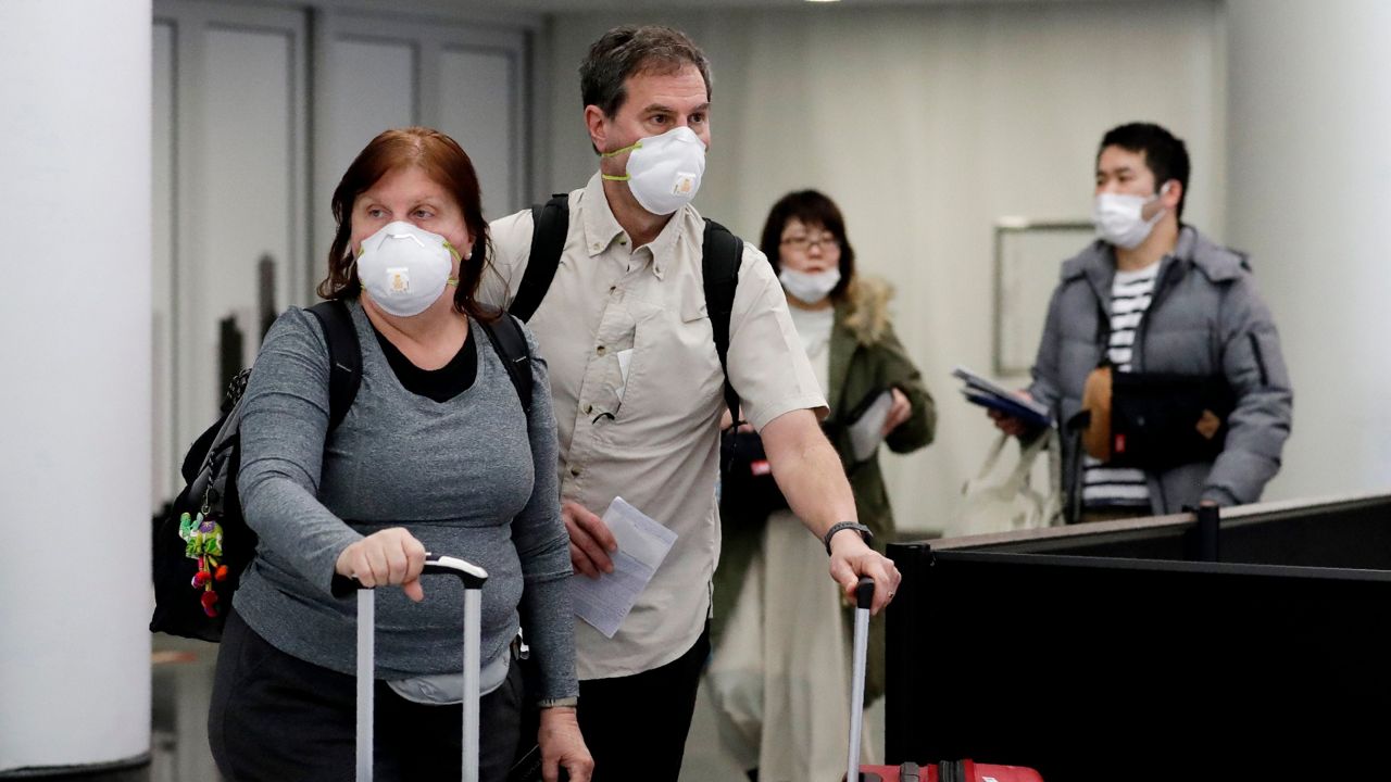 Travelers wear protective mask as they walk through in terminal 5 at O'Hare International Airport in Chicago, Sunday, March 1, 2020. (AP Photo/Nam Y. Huh)
