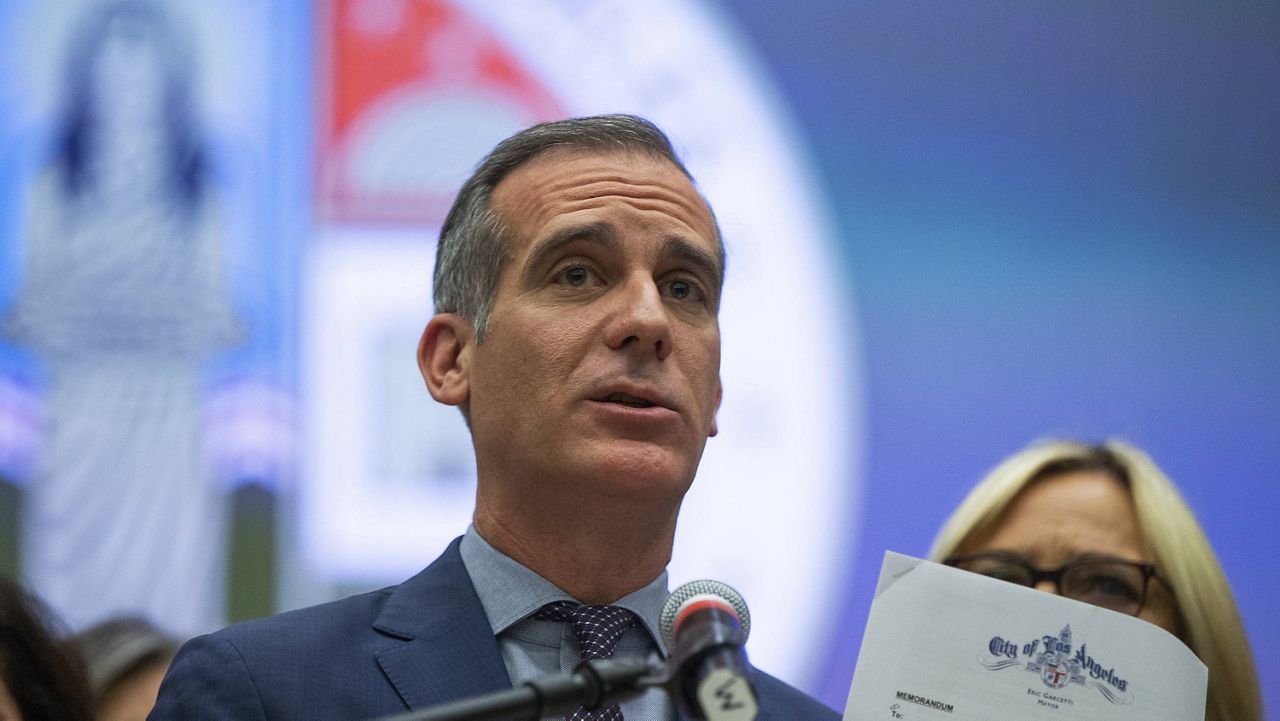 Los Angeles Mayor Eric Garcetti shows a Memorandum with COVID-19 city departments guidelines, as he takes questions at a news conference in Los Angeles, Thursday, March 12, 2020. Garcetti closed City Hall to the public and banned all events or conferences on city-owned properties for more than 50 people. (AP Photo/Damian Dovarganes)