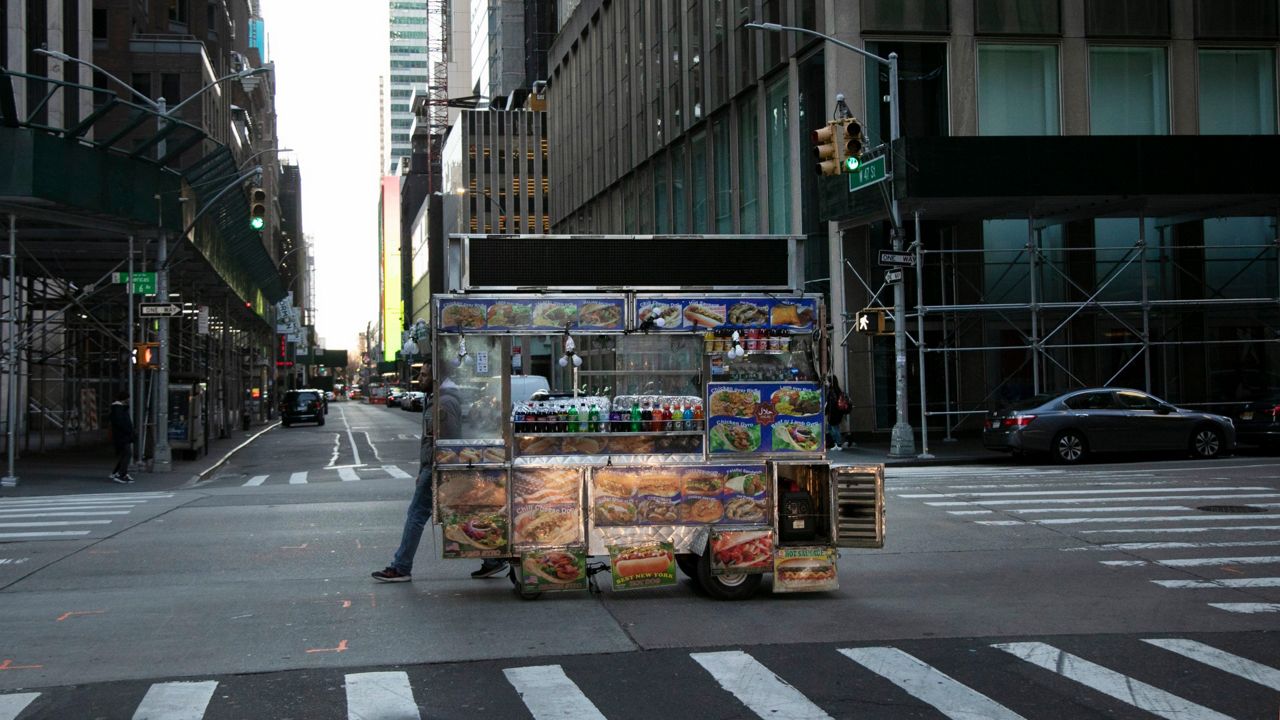 A food truck vendor pushes his cart down an empty street near Times Square in New York, on Sunday, March 15, 2020.