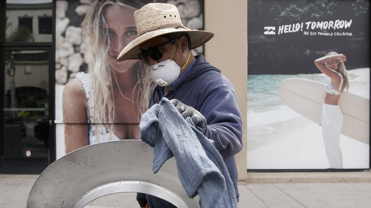 Isabel James cleans Main Street after nonessential businesses and activities were curtailed due to the coronavirus, March 20, 2020, in Huntington Beach, Calif. (AP/Chris Carlson)