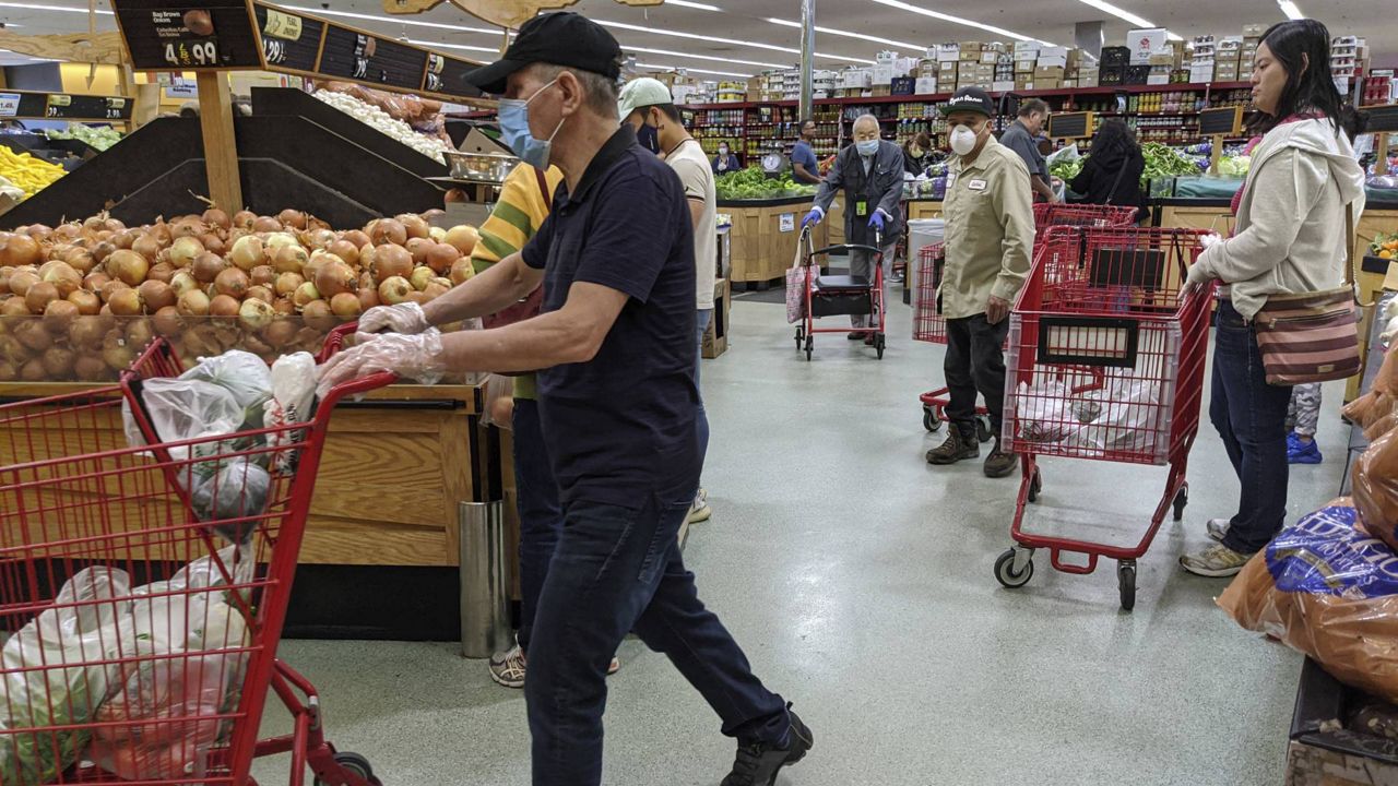 Several customers at Super King Markets grocery store wear face masks and gloves on April 3, 2020 in Los Angeles, as protection against the coronavirus. (AP Photo/Damian Dovarganes)