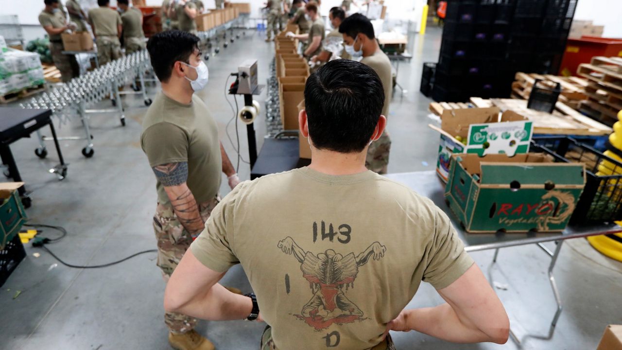 Texas National Guard Specialist Ercan Novelo, center, waits for a box to load onto a waiting pallet in Plano, Texas, Tuesday, April 7, 2020. (AP Photo)