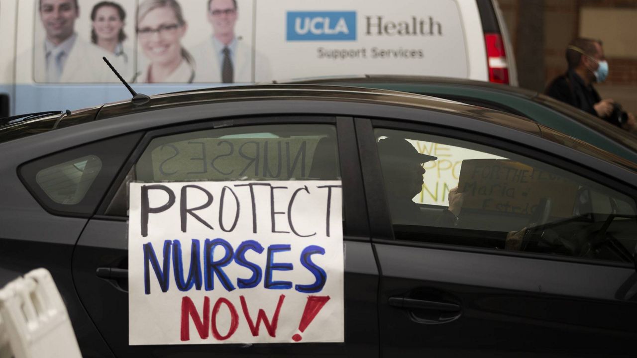 FILE - Health care workers drive by to express their support for nurses protesting the lack of Personal Protective Equipment outside the UCLA Medical Center, April 13, 2020. (AP/Damian Dovarganes)