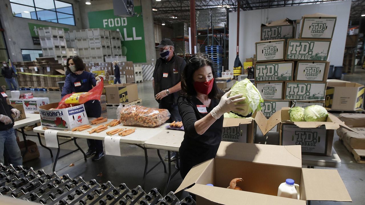 San Francisco-Marin Food Bank volunteers pack food into bags to be delivered to people during the coronavirus pandemic in San Rafael, Calif., Saturday, April 18, 2020. (AP Photo/Jeff Chiu)