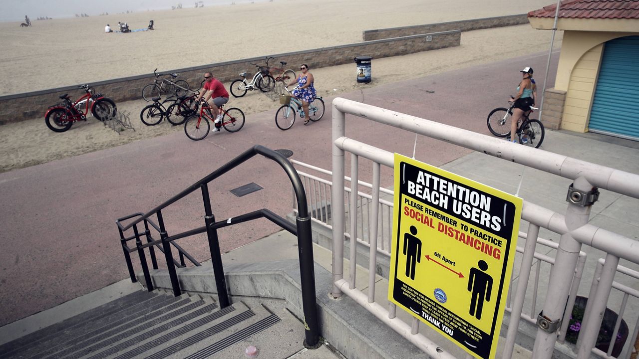 A sign encourages people to practice social distance Sunday, April 26, 2020, in Huntington Beach, Calif. (AP Photo/Marcio Jose Sanchez)