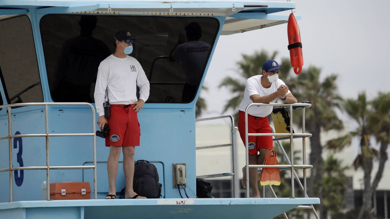 Lifeguards wear masks while watching beach goers in Huntington Beach, Calif. (AP Photo/Marcio Jose Sanchez)