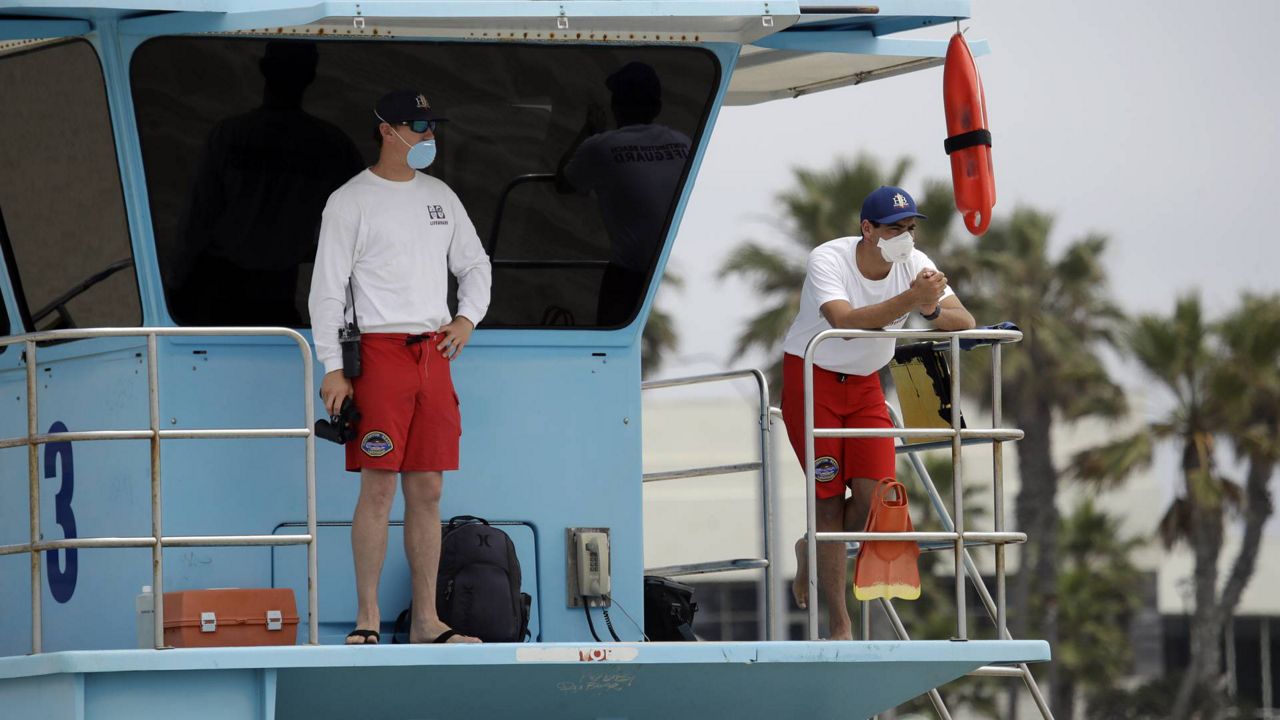 Lifeguards wear masks while watching beach goers Thursday, April 30, 2020, in Huntington Beach, Calif. (AP Photo/Marcio Jose Sanchez)