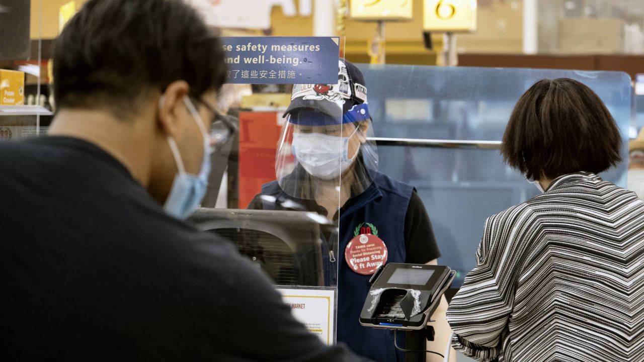 A grocery worker helps check out a customer from behind a plexiglass barrier at the 99 Ranch Market in the Van Nuys section of L.a. on May, 5, 2020. (AP/Richard Vogel)
