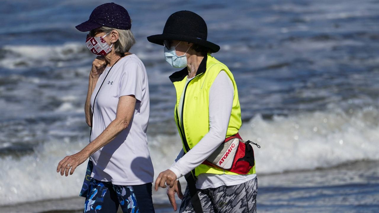 Beach goers walk on the sand on Wednesday, May 13, 2020, in Manhattan Beach, Calif. (AP/Ashley Landis)