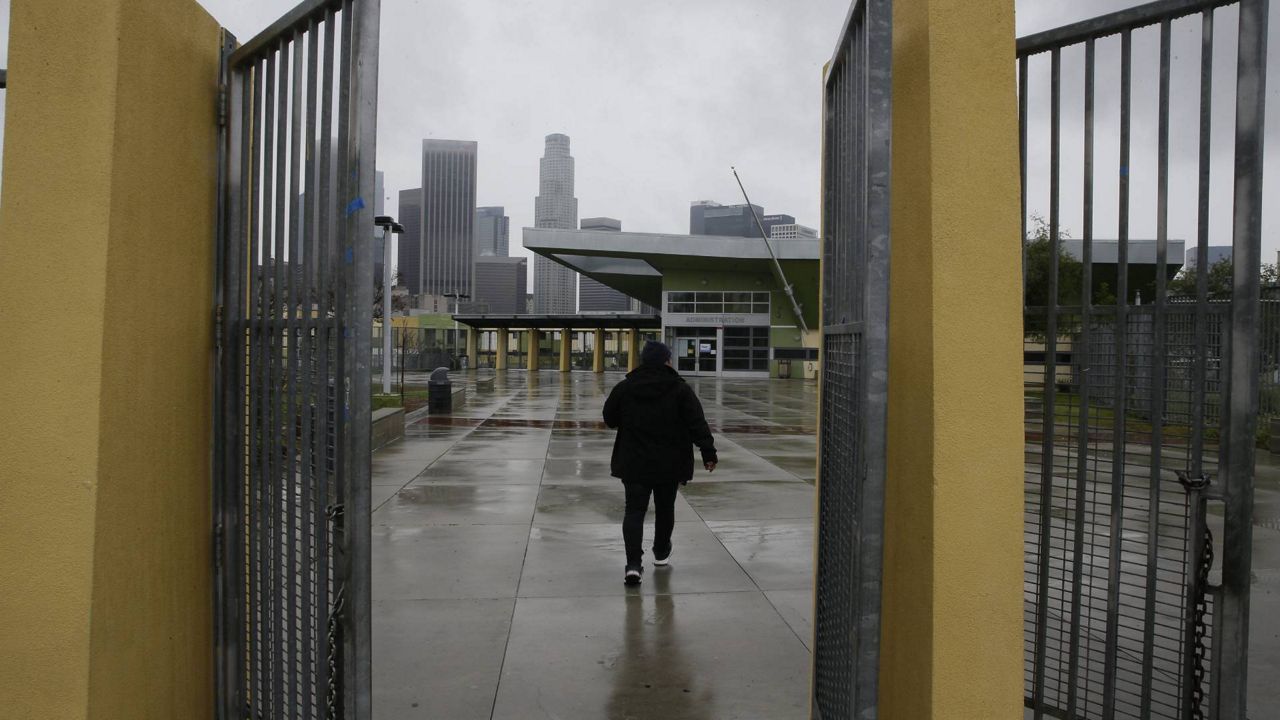In this March 13, 2020, file photo, a parent arrives at the Edward R. Roybal Learning Center in L.A., to pick up a student after LAUSD announced the closure of schools for two weeks. (AP/Damian Dovarganes)