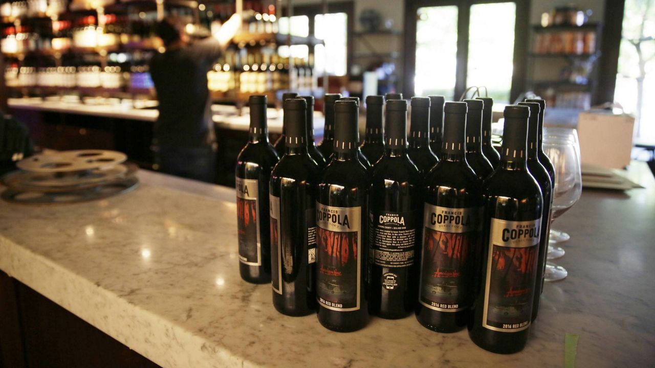 Bottles of Apocalypse Now Red Blend wine are seen on a tasting bar counter as Jesse Cierly restocks a shelf at the Francis Ford Coppola Winery, May 21, 2020, in Geyserville, Calif. (AP/Eric Risberg)